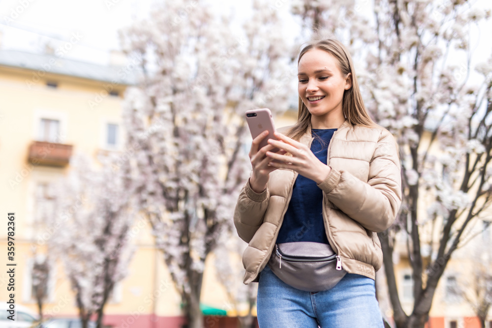 Portrait of attravtive young woman use smartphone on Background of pink tree Portrait of attravtive young woman use smartphone on Background of pink tree