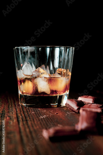 malt scotch whiskey with ice and chocolate on wooden table