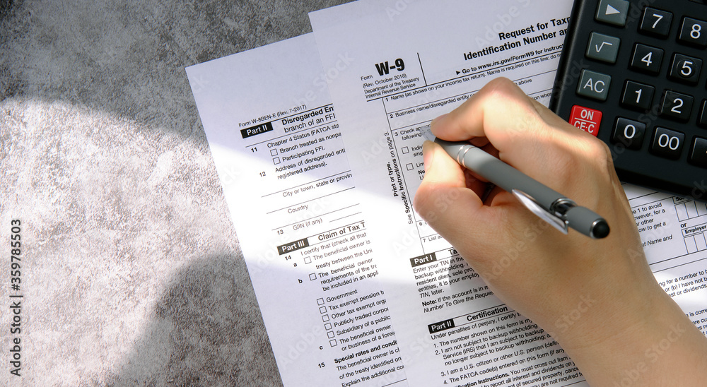 Naklejka premium Filling out a tax form and counting taxes on the calculator