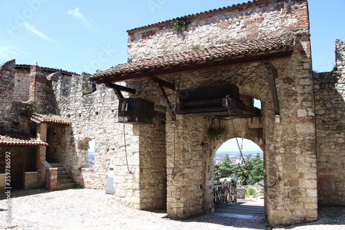 Stone wall with merlons and drawbridge gate of medieval castle of Brescia in north Italy photo