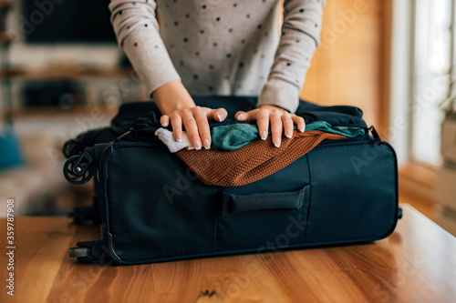 Woman packing a luggage for travel, close-up.