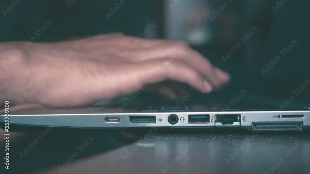 Manos de hombre escribiendo en la computadora portátil, sobre un escritorio, vista de cerca.
