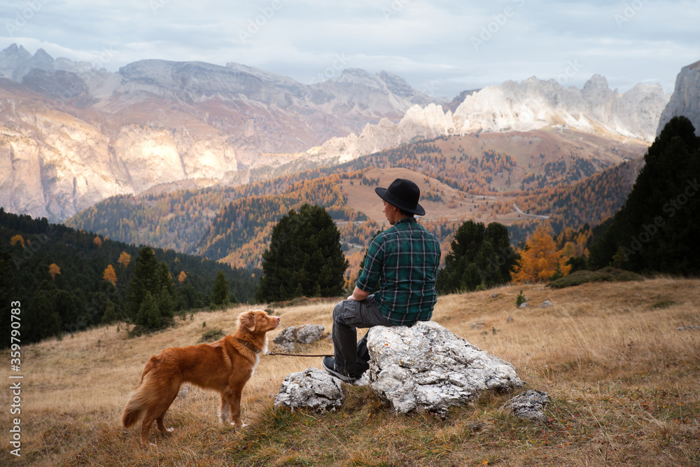 man with a dog in the mountains. travel, hiking with a pet. Nova Scotia Duck Tolling Retriever