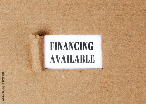 Financing. Available text on a white background appearing on a torn cardboard.