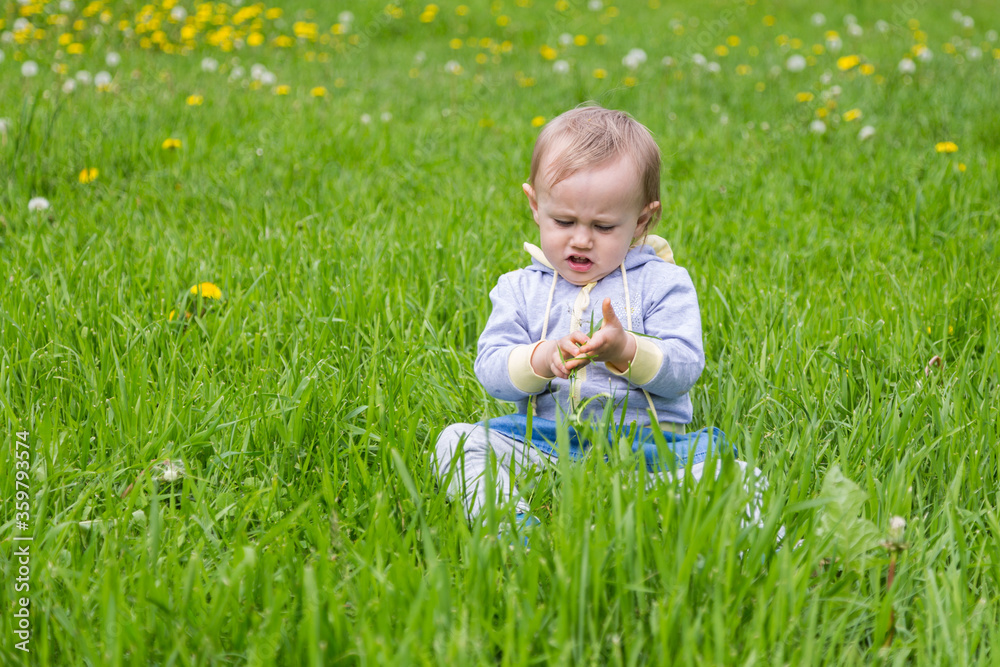 Young blonde girl standing on the green grass. Young blonde girl standing on the green grass.