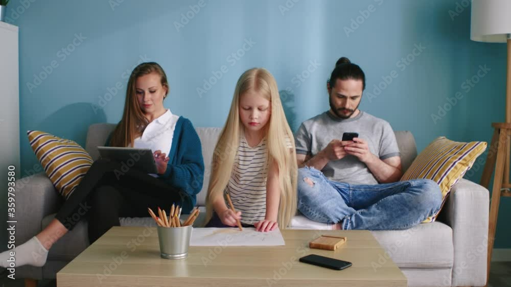 Young family is spending leisure time at home, preferring their hobbies rather than communication, parents spend time online, small daughter is drawing, Slow motion.