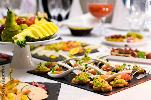 A variety of mini snacks with different fillings on a plate. Cold appetizers and slices in a restaurant on a banquet table with delicacies on spoons and in plates