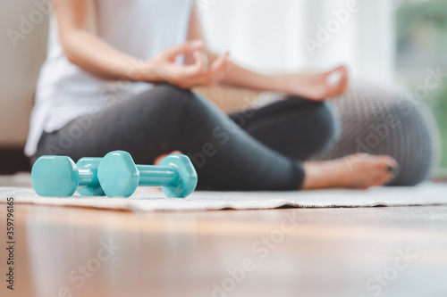 dumbbell on the floor with woman doing meditation