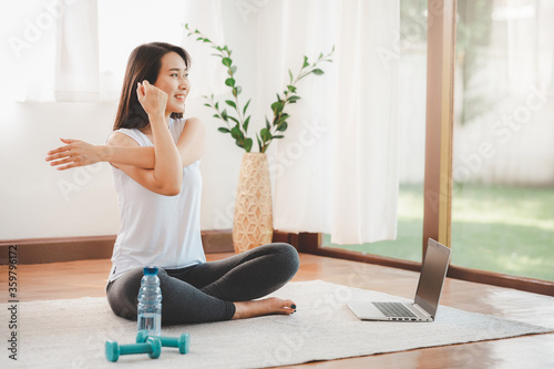 Asian woman doing yoga shoulder stretching online class at home photo