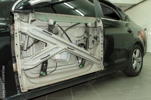 The car with the front door panel removed is in a car repair shop.