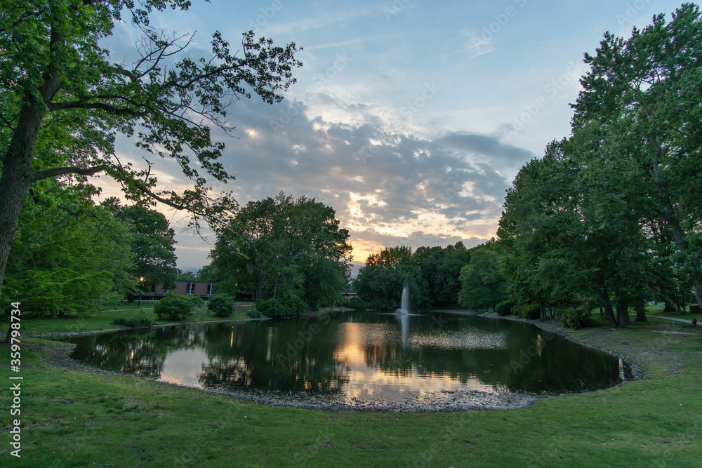 Fototapeta premium East Brunswick, New Jersey - May 25, 2019: A landscape view of a local pond can be found in the heart of the town with a sidewalk wrapping around it for a scenic and leisurely stroll. 