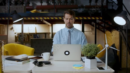 Man with laptop sitting indoors at desk in home office, working. photo