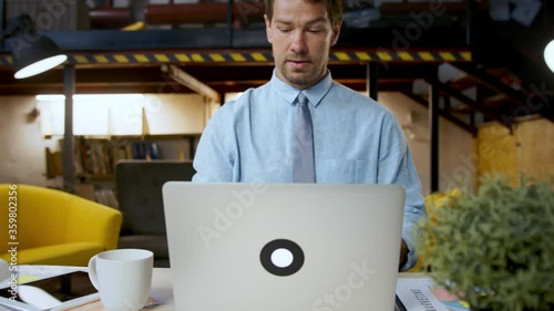 Man with laptop sitting indoors at desk in home office, working. photo