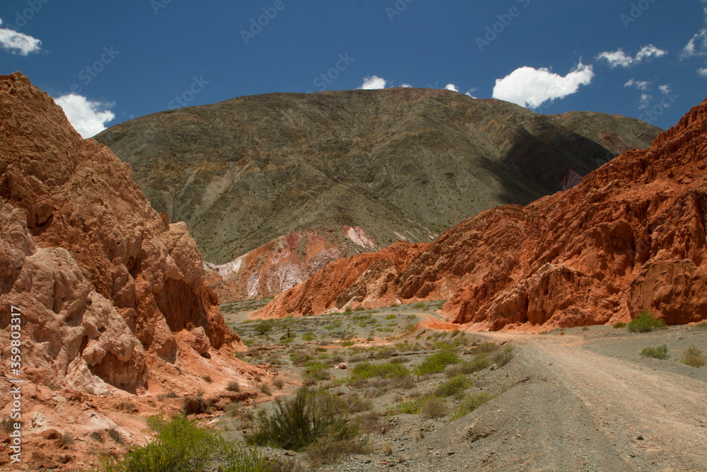 Red and orange rocky formations. Footpath across the colorful mountains. 