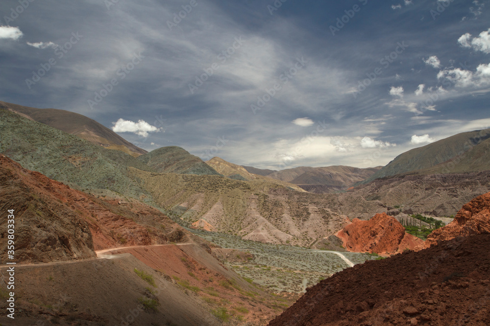 Desert landscape. Geology. Colorful rocky formations. Dirt road across the mountains. 