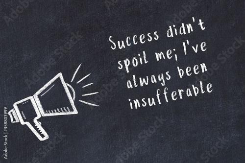 Chalk sketch of loudspeaker on black desk and movitational quote