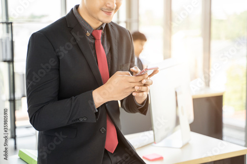 concept asian businessman entrepreneur employee using mobile phone contacting messaging customers, working in modern office, team work with colleague planning brainstorming business ideas and strategy