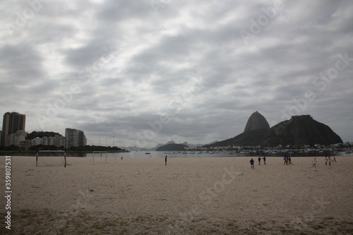 people play soccer on beach with View of Sugarloaf Mountain and Rio de Janeiro Skyline, Brazil.