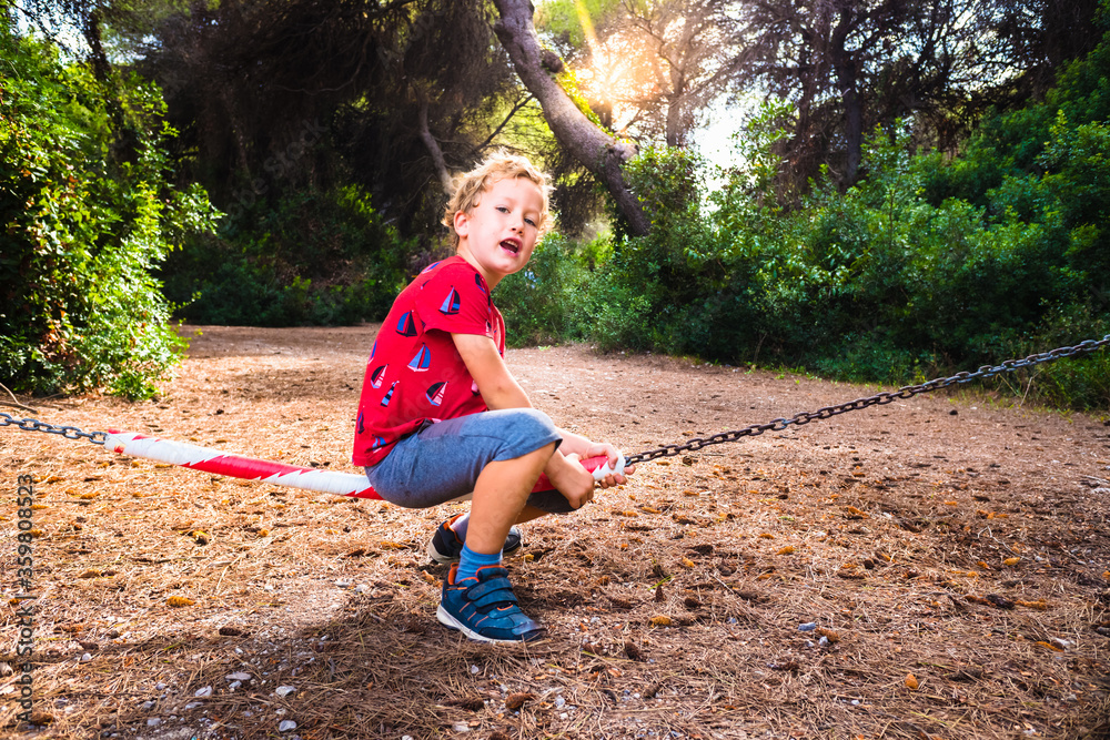 Young boy plays swinging on a barrier of prohibited passage in a forest, concept of challenge of limits. Young boy plays swinging on a barrier of prohibited passage in a forest, concept of challenge of limits.