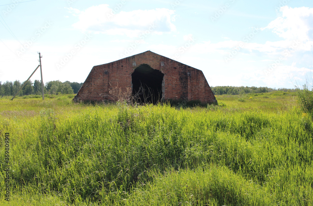 Obraz premium destroyed abandoned building ruins with an opening for the farm hangar