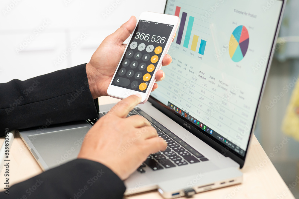 Asian accountant working, calculate and analyzing report project accounting with notebook, calculator in mobile phone in modern office : finance and business