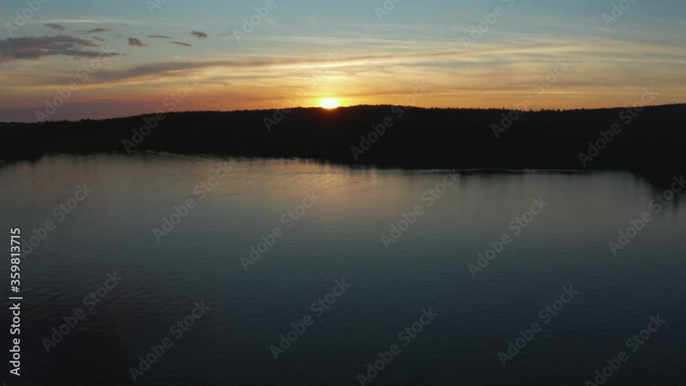 Drone flying over a quiet lake going towards a colorful sunset, in the Eastern Township, Quebec, Canada Drone flying over a quiet lake going towards a colorful sunset, in the Eastern Township, Quebec, Canada