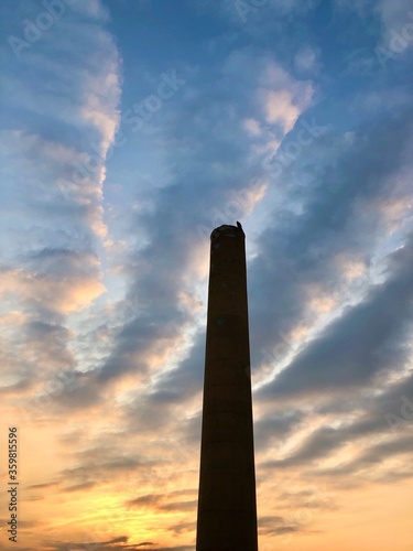 Tall chimney smokestack against sunrise