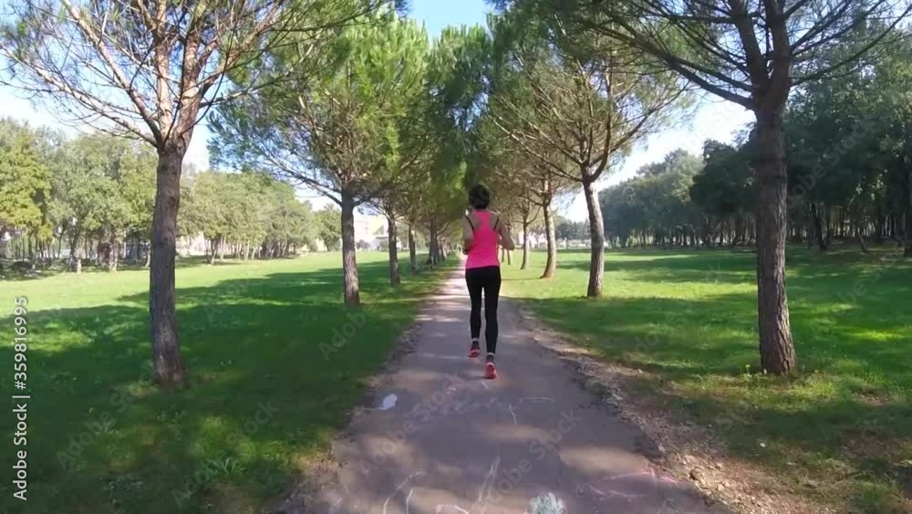 Slow motion of a girl running. Runner's back. Run in a park tree avenue. Slow motion of a girl running. Runner's back. Run in a park tree avenue.