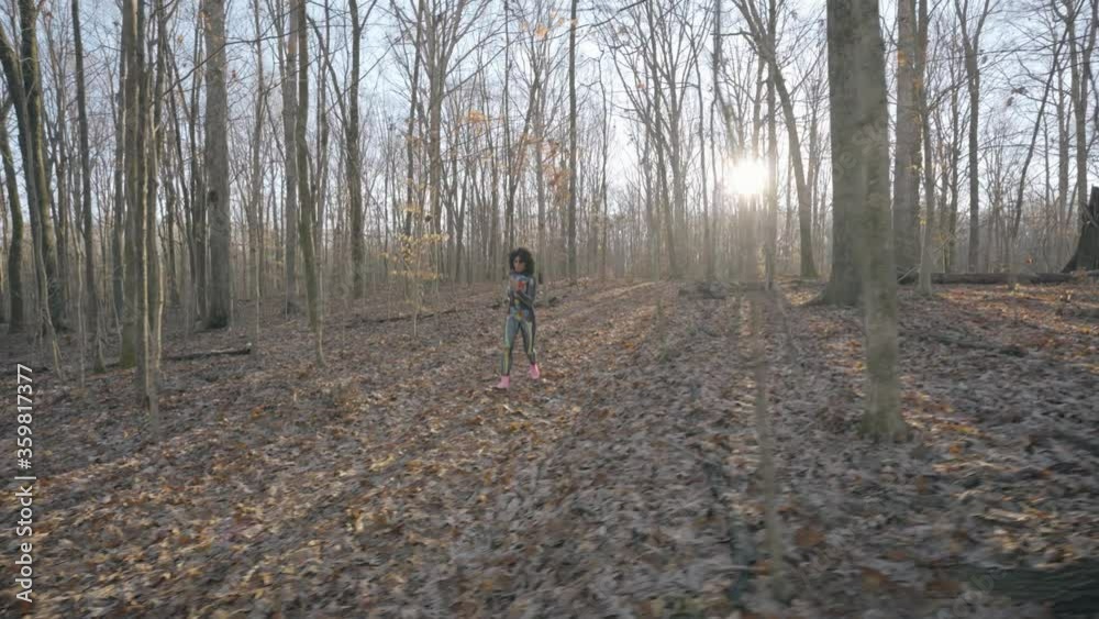 Woman in colorful skull suit running through the woods