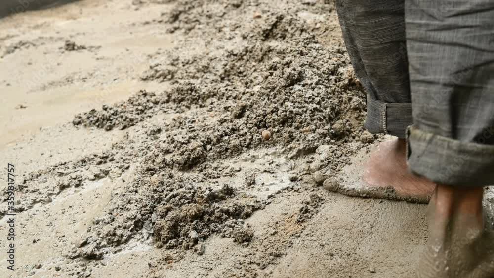 Indian labour mixing cement and water manually on floor using a shovel. Stock footage.