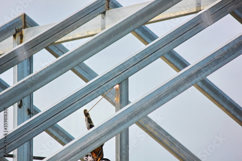 the worker welding metal on roof structure