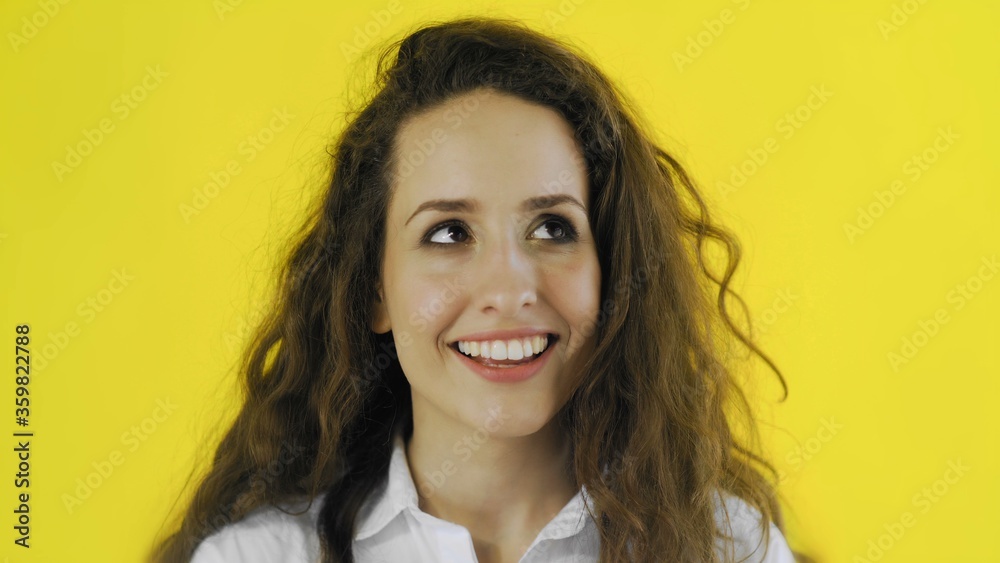 Beautiful woman is looking at camera flirting and smiling on yellow background Beautiful woman is looking at camera flirting and smiling on yellow background
