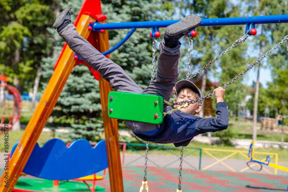 Fototapeta premium happy boy rides on a swing in the park