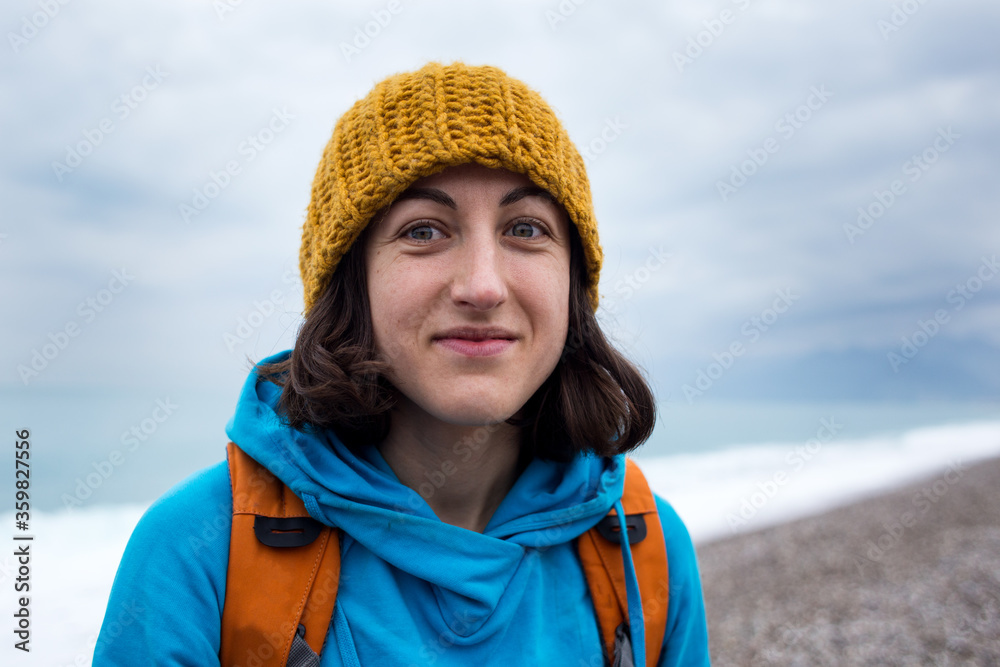 Portrait of a smiling girl in a knitted hat while walking along the sea coast.