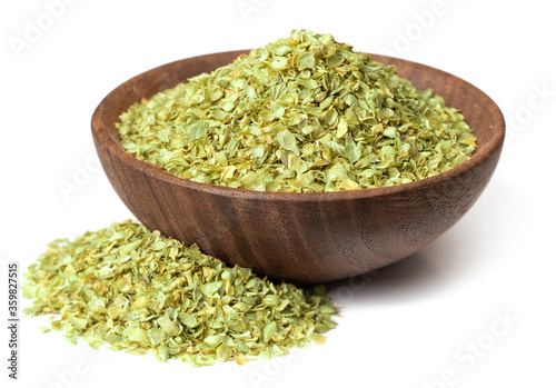 dried oregano flakes in the wooden bowl, isolated on white background