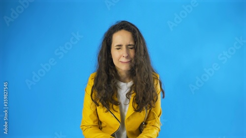 Disappointed and a very sad young woman almost crying in Studio with blue Background.