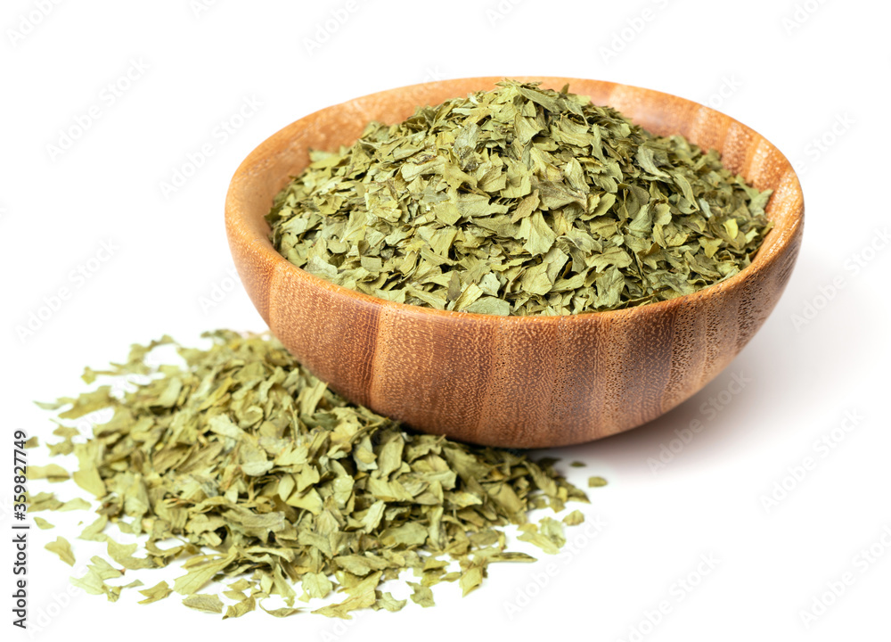 dried parsley flakes in the wooden bowl, isolated on white background dried parsley flakes in the wooden bowl, isolated on white background