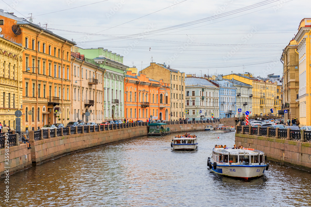 Naklejka premium Waterfront buildings on the banks of river Neva and tourist boats on the water in Saint Petersburg