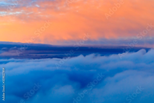 Colorful fluffy clouds outside an airplane at sunset