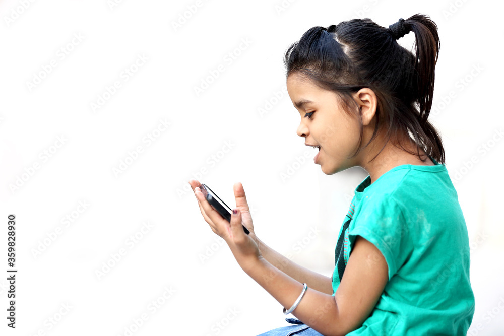 A young indian girl excited watching mobile phone. Happiness in mobile. Joyful baby girl. Excited baby girl. Playing with mobile. A young indian girl excited watching mobile phone. Happiness in mobile. Joyful baby girl. Excited baby girl. Playing with mobile.