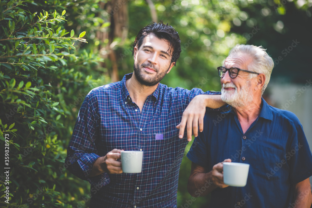 An adult hipster son and senior father at home, holding a cup of coffee in the morning An adult hipster son and senior father at home, holding a cup of coffee in the morning