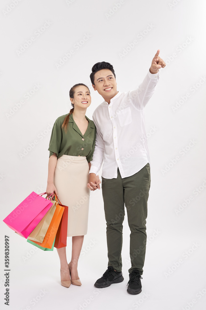 couple with shopping bags, man pointing at copy space on sky. couple with shopping bags, man pointing at copy space on sky.