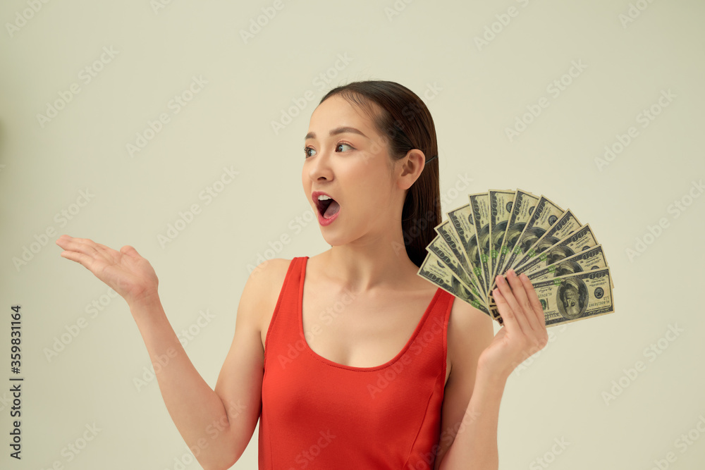 Portrait of an excited beautiful young woman standing isolated over light background, showing money banknotes Portrait of an excited beautiful young woman standing isolated over light background, showing money banknotes
