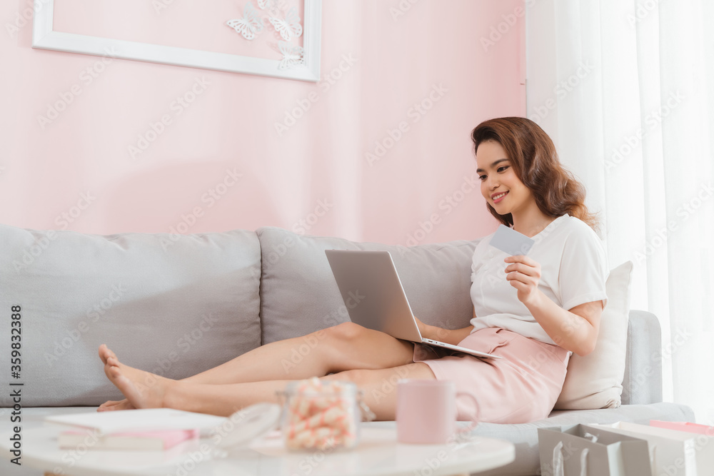 Pretty woman doing online shopping with laptop at home in the living room Pretty woman doing online shopping with laptop at home in the living room