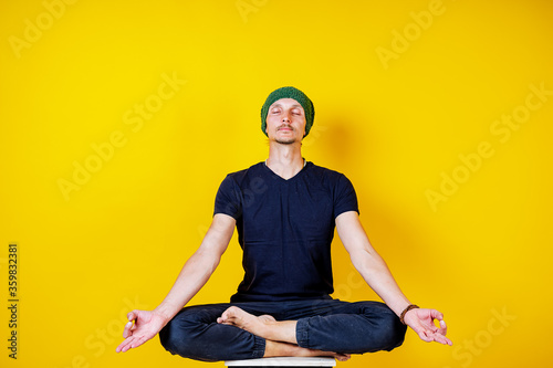 white male hipster doing yoga on a yellow background, yoga exercises and asanas, meditation, calm