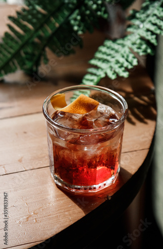 cold refreshing Old Fashioned cocktail with orange on a wood on a summer sunny day
