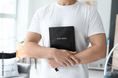 Young man with Bible at hom...