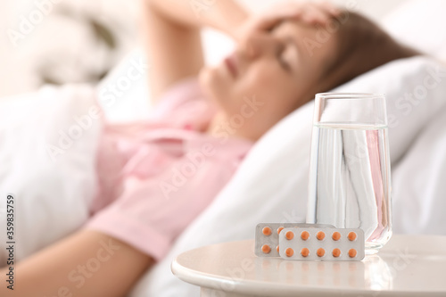 Sleeping pills on table in bedroom of young woman