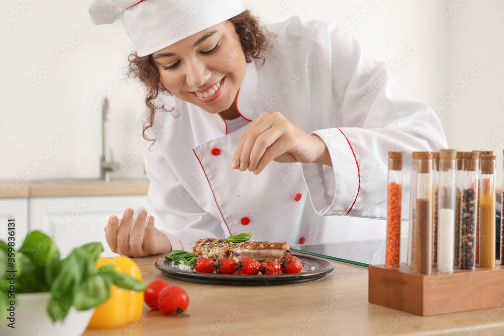 Female African-American chef with tasty dish in kitchen Female African-American chef with tasty dish in kitchen