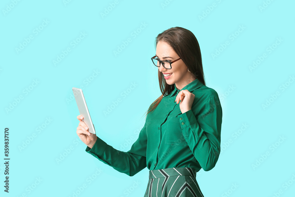 Beautiful young woman in stylish shirt and with tablet on color background Beautiful young woman in stylish shirt and with tablet on color background